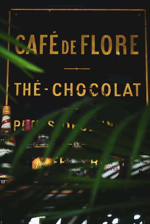 Das alte Café-de-Flore-Schild hinter Palmwedeln, goldene Schrift auf Schwarz