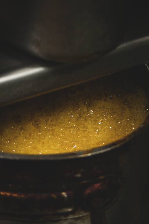 Goldene Sauce köchelt im Topf, ganz nah – nur Blasen und warmes Licht